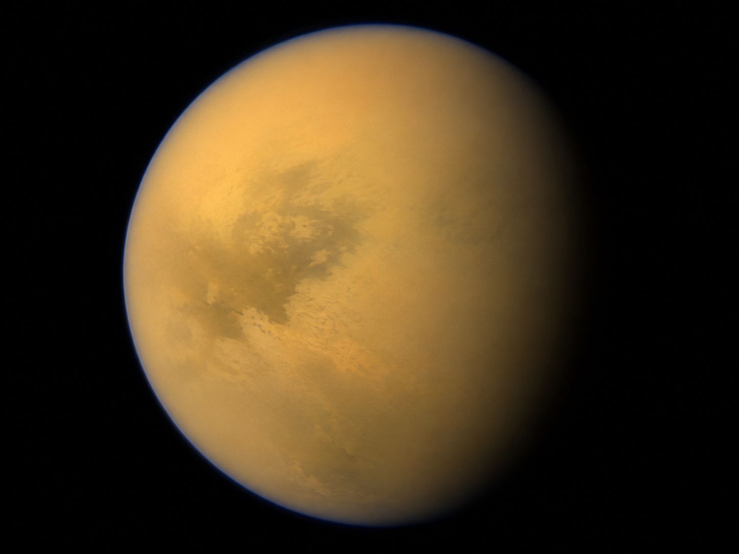 Saturn's biggest moon Titan, photographed by Cassini showing its thick orange-yellow atmosphere
